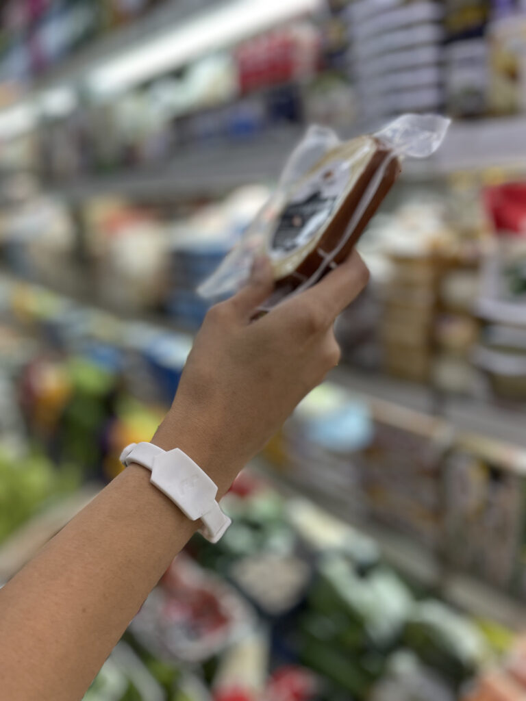 Wrist of person wearing the Tapr band while shopping for groceries.